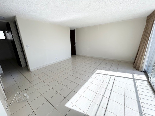 A room with white tiled flooring and a window with curtains.